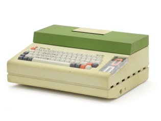 Με 12 κιλά βάρος, ο Scrib είναι ένας από τους πρώτους φορητούς υπολογιστές. Κάτω από το πληκτρολόγιο υπάρχει οθόνη CRT 7'' και το περιεχόμενό της διαβάζεται από τον καθρέφτη που είναι τοποθετημένος στο πάνω μέρος του υπολογιστή.